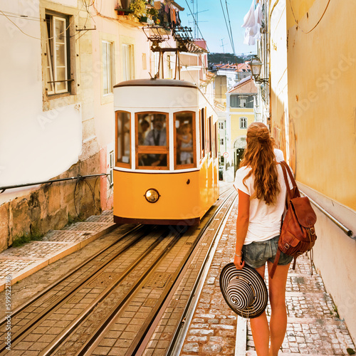 Traveler woman waiting yellow traditional tram on a street in Lisbon- Portugal photo