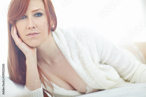Foto Portrait of beautiful redhead lying alone on a bed at home