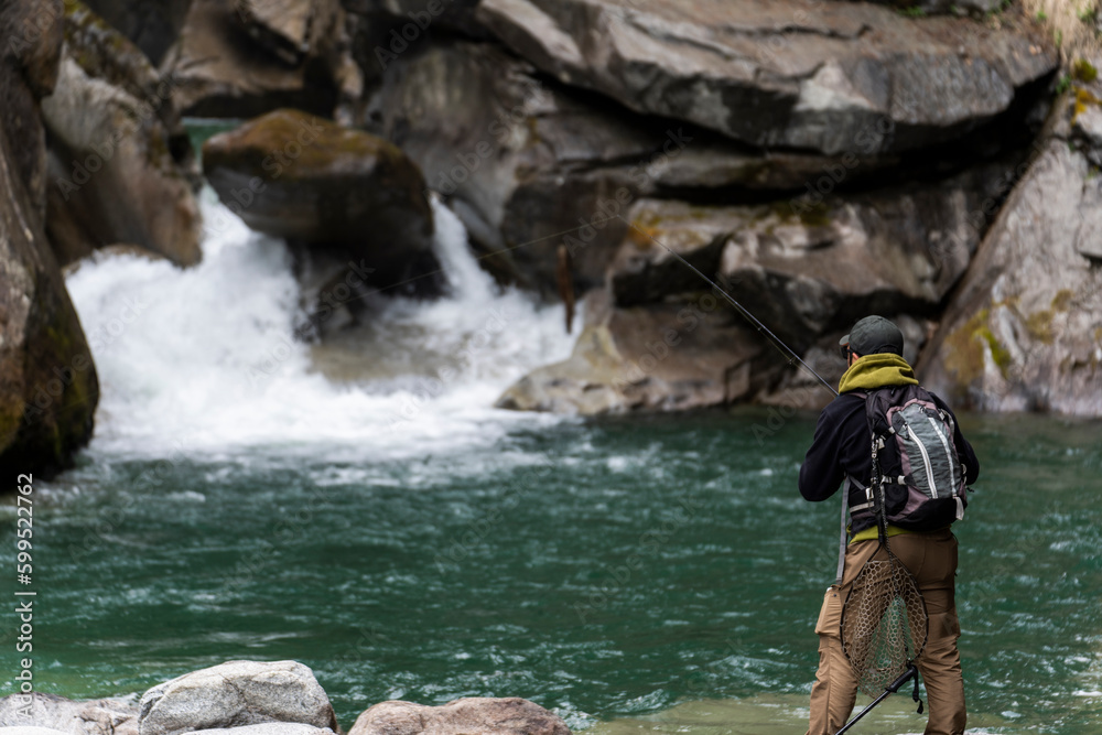 Pescatore in azione durante una battuta di pesca nelle acque di un torrente montano in Trentino Alto Adige, Italia Pescatore in azione durante una battuta di pesca nelle acque di un torrente montano in Trentino Alto Adige, Italia