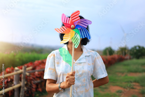 A woman shows a small windmill that covers her face to convey the importance of wind energy and clean energy.