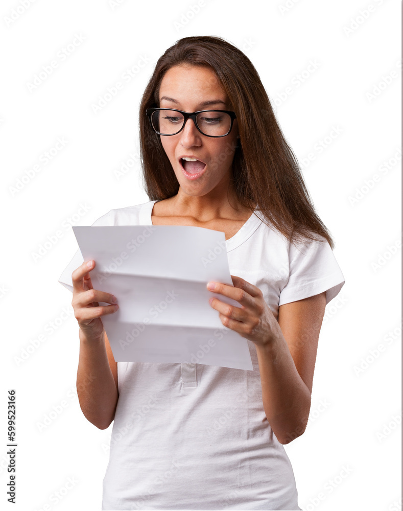 Emotional portrait of a young woman isolated on a neutral background. She has her mouth wide open and jaw lowered due to shock from the news in the letter she's holding. She has glasses, long brown ha