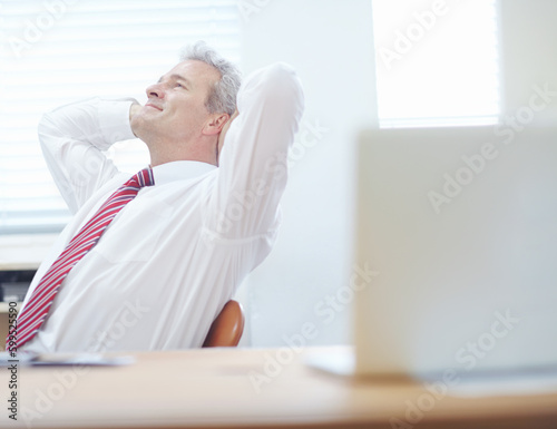 Thinking about success. Relaxed businessman leaning back in an office chair with his hands behind his head.