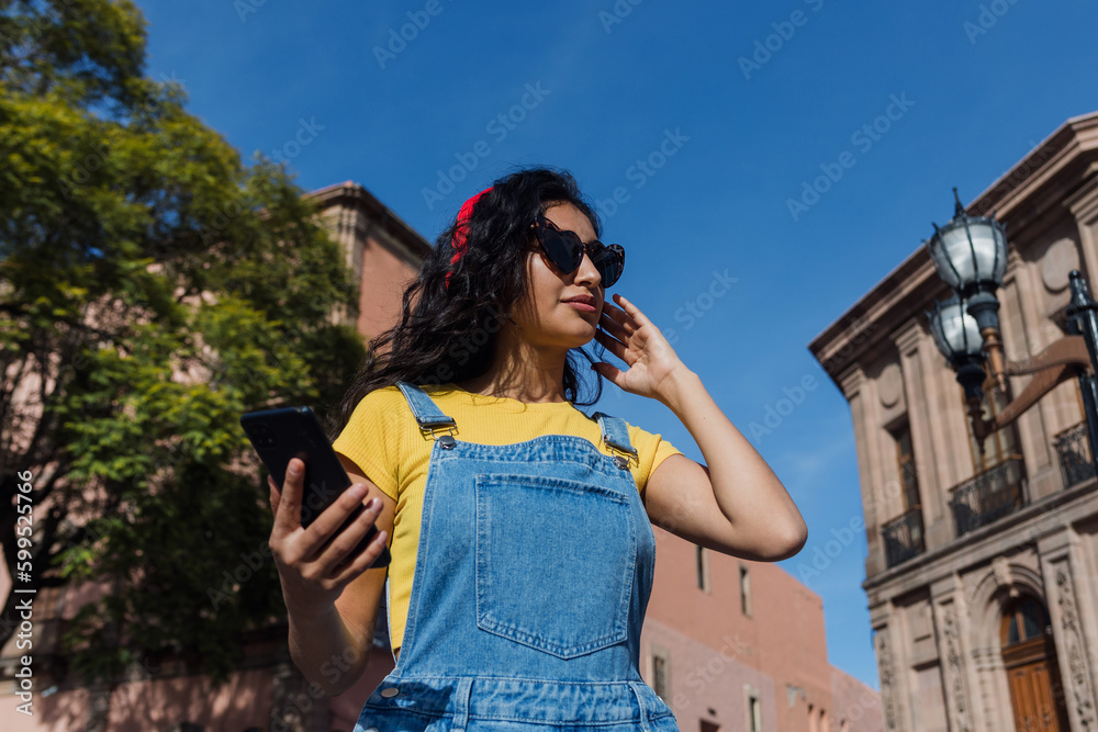 latin young woman with headphones listening music on public park in Mexico Latin America, hispanic girl