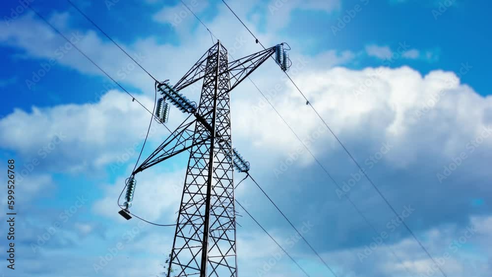 Power transmission lines against blue sky with white clouds