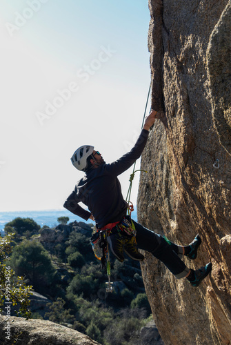Young adult climbing a granite wall at Torrelodones, Madrid. Rock climbing. Extreme sports concept