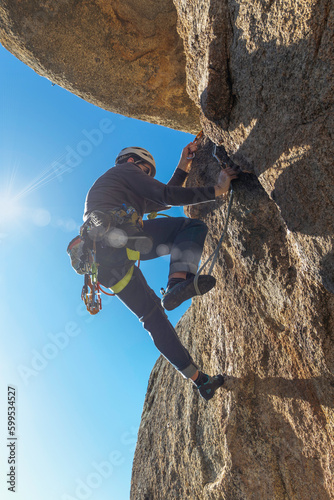 Young adult climbing a granite wall at Torrelodones, Madrid. Rock climbing. Extreme sports concept photo