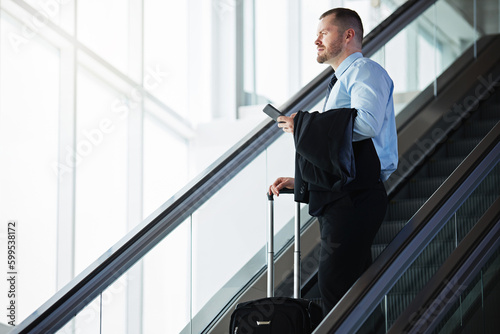 Big world, big career dreams. a businessman traveling down an escalator in an airport.