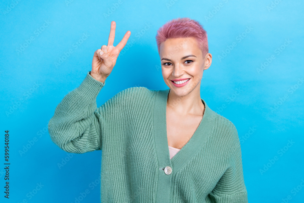 Portrait photo of young friendly person pink dyed hair woman wear green trendy shirt show v-sign peace isolated on blue color background Portrait photo of young friendly person pink dyed hair woman wear green trendy shirt show v-sign peace isolated on blue color background