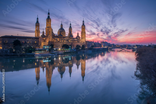 del Pilar basilica, one of the important architectural symbols of zaragoza, and the Ebro river and its reflection with sunset colors and clouds © Aytug Bayer