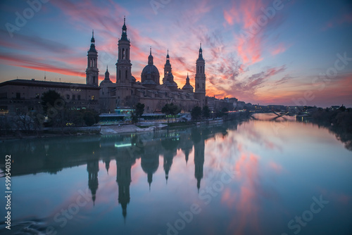 del Pilar basilica, one of the important architectural symbols of zaragoza, and the Ebro river and its reflection with sunset colors and clouds © Aytug Bayer