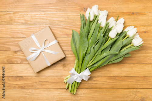 White tulip bouquet and gift box on wooden background  top view