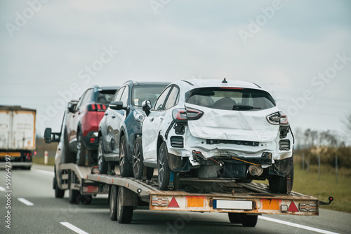 Tow truck with broken car on country road. Tow truck transporting car on the highway. Car service transportation concept. © AlexGo