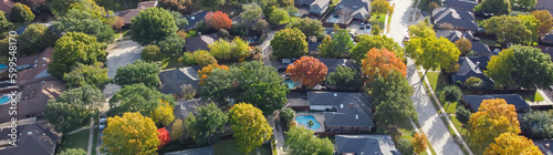 Panorama quite curved residential street and colorful autumn leaves surrounding residential houses with swimming pool, fenced backyard in upscale neighborhood Dallas, Texas, USA