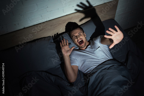 Quadro su tela top view of man having anxiety and screaming while having nightmares at night