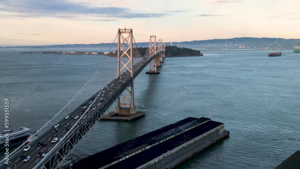 Cinematic flying around San Francisco Bay Bridge to discover the downtown skyscrapers in pink sunrise light. San Francisco USA, suspension bridge iconic landmark of California. Establishing shot Cinematic flying around San Francisco Bay Bridge to discover the downtown skyscrapers in pink sunrise light. San Francisco USA, suspension bridge iconic landmark of California. Establishing shot