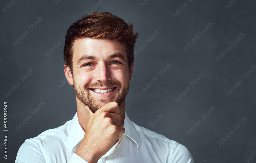 Off the charts kinda handsomeness. Studio shot of a handsome young man posing against a grey background.