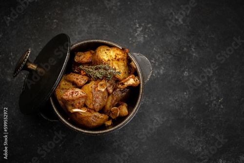 Fried potatoes with garlic and spices in a small cast-iron pot © pobaralia