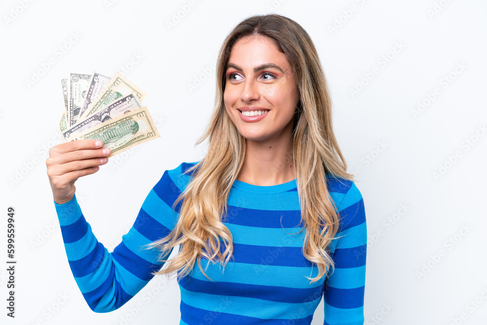 Young Uruguayan woman taking a lot of money isolated on white background looking side Young Uruguayan woman taking a lot of money isolated on white background looking side