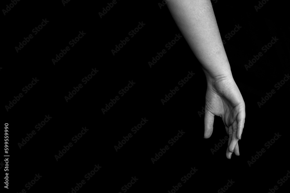Fototapeta premium black and white female hands with closed fingers on dark background with copyspace for your text