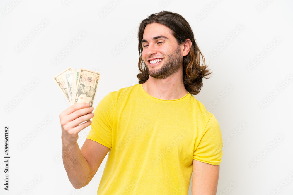 Young handsome man taking a lot of money isolated on white background with happy expression Young handsome man taking a lot of money isolated on white background with happy expression