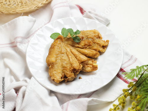 Banana fritters in white ceramic plate. In Indonesia it called pisang goreng kipas. selective focus