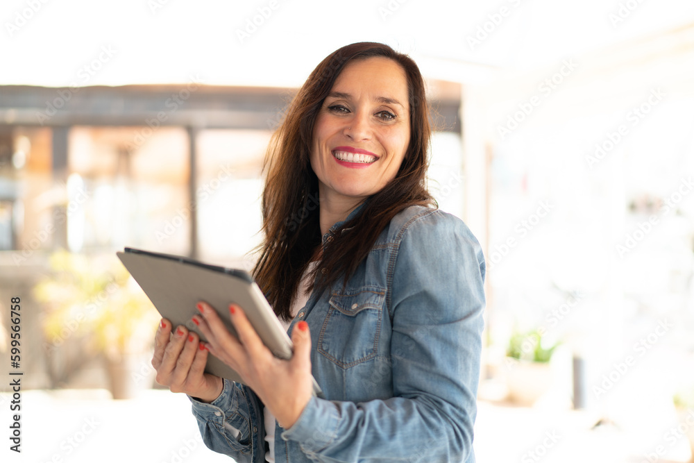 Middle aged woman holding a tablet with happy expression