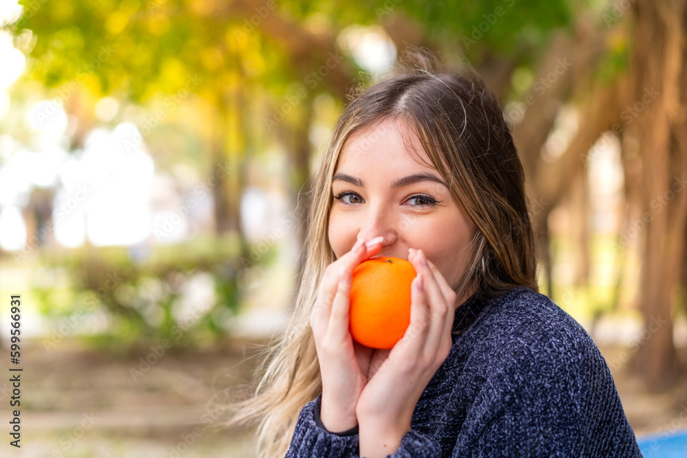 Young pretty Romanian woman holding an orange at outdoors Young pretty Romanian woman holding an orange at outdoors