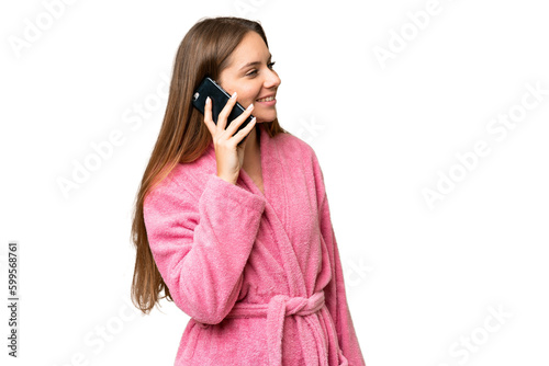 Young woman in a bathrobe over isolated chroma key background keeping a conversation with the mobile phone with someone