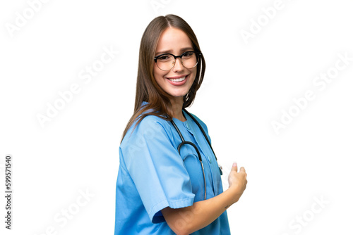 Young nurse caucasian woman over isolated background pointing back