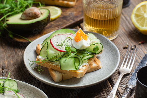 White bread toasts with cream cheese, egg, avocado, cucumber and radish in a plate
