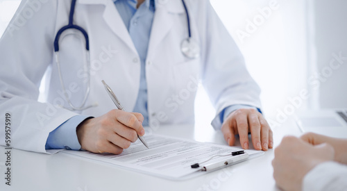 Stethoscope lying on the tablet computer in front of a doctor and patient sitting opposite each other at the background . Medicine, healthcare concept