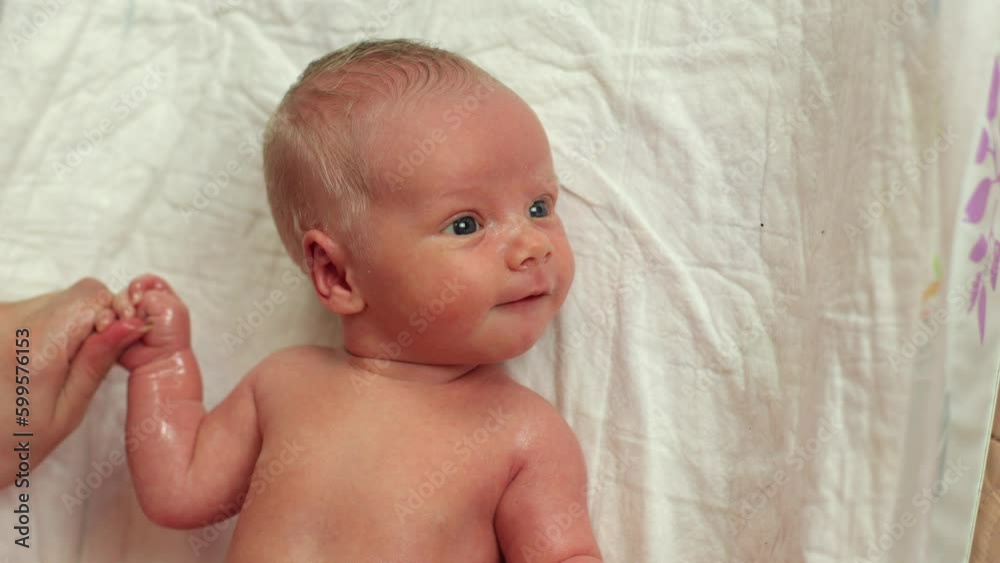 A newborn baby. Before bathing, the child is given a massage. The first days of a two-week-old baby's life. A child with white hair. Joy for parents, a newborn boy. Children's procedures A newborn baby. Before bathing, the child is given a massage. The first days of a two-week-old baby's life. A child with white hair. Joy for parents, a newborn boy. Children's procedures