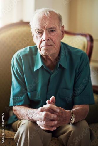 Its not so bad once you get used to it. Cropped portrait of a senior man sitting by himself in a living room. photo