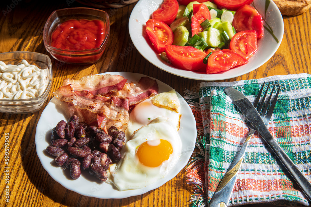 Fried eggs, bacon and beans on a wooden table...vegetable for the breakfast...