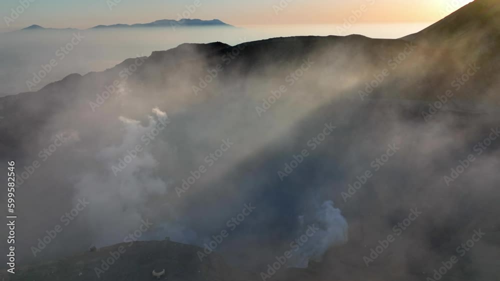 Volcanic landscape at sunrise with smoke rising from the crater, aerial ...