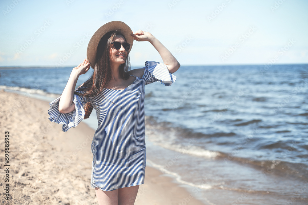 Portrait of a happy smiling brunette woman standing on ocean beach and looking at the camera Portrait of a happy smiling brunette woman standing on ocean beach and looking at the camera