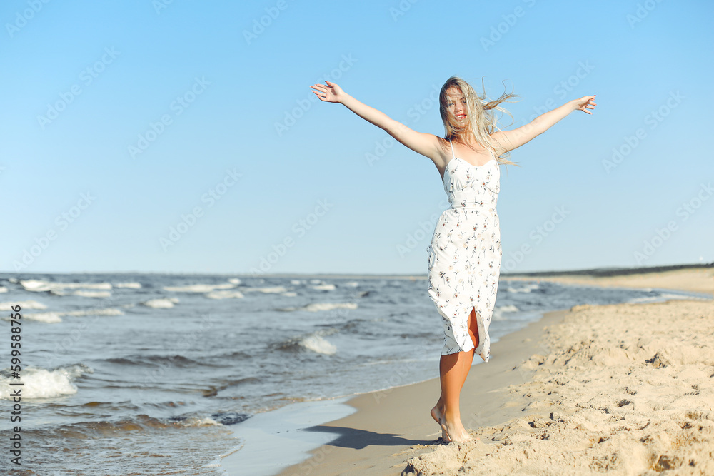 Happy blonde woman wearing sun glasses and relaxing on a wooden deck chair at the ocean beach Happy blonde woman wearing sun glasses and relaxing on a wooden deck chair at the ocean beach