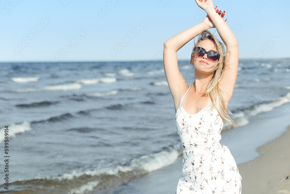 Happy blonde woman wearing sun glasses and relaxing on a wooden deck chair at the ocean beach