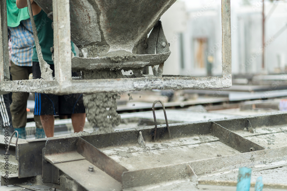 A male worker in a precast wall manufacturing factory (Precast) is pouring cement in a prepared mold to form a wall. A male worker in a precast wall manufacturing factory (Precast) is pouring cement in a prepared mold to form a wall.