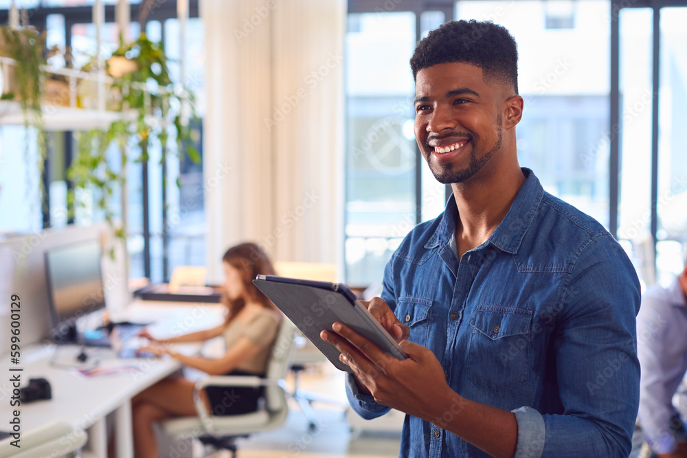 Young Smiling Businessman With Digital Tablet Standing And Working In Modern Office Young Smiling Businessman With Digital Tablet Standing And Working In Modern Office