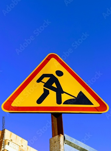 sign of a man digging with a shovel against a blue sky