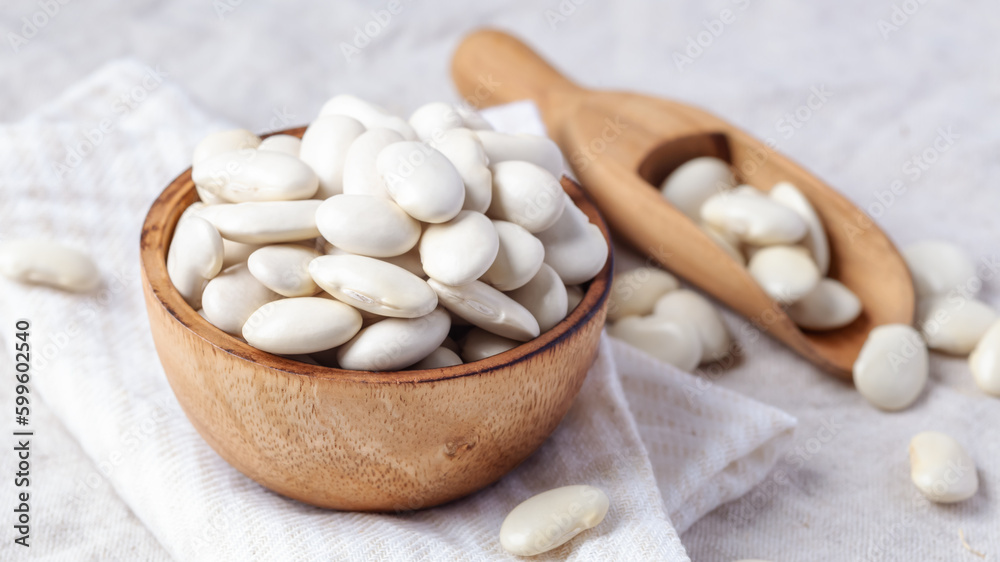 White beans in wooden bowl with scoop on linen tablecloth White beans in wooden bowl with scoop on linen tablecloth