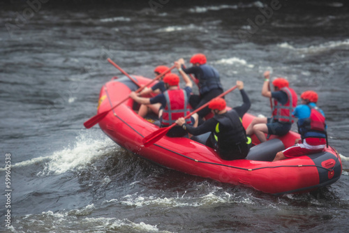 Red raft boat during whitewater rafting extreme water sports on water rapids, group of sportsmen in wetsuits kayaking and canoeing on the river, water sports team with a big splash of water