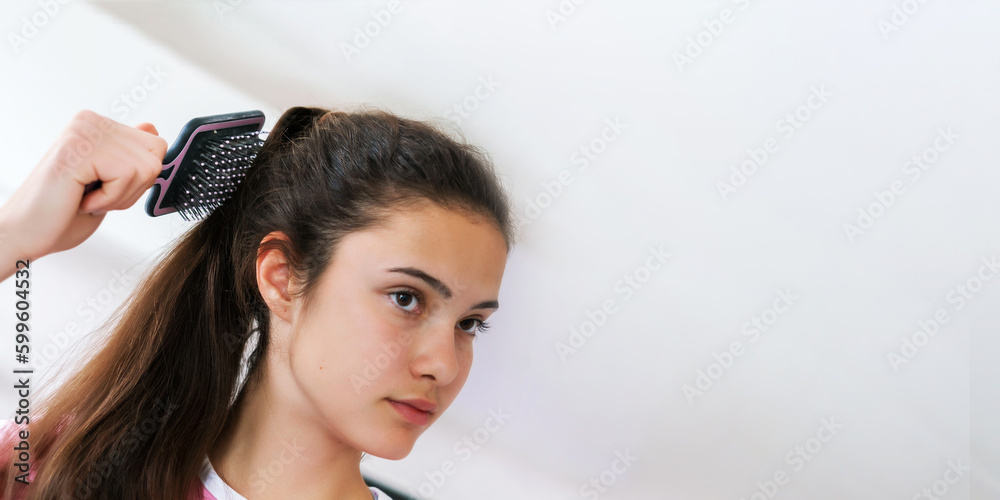 schoolgirl brushes long ponytail with stylish hairbrush against bathroom wall in morning close view schoolgirl brushes long ponytail with stylish hairbrush against bathroom wall in morning close view
