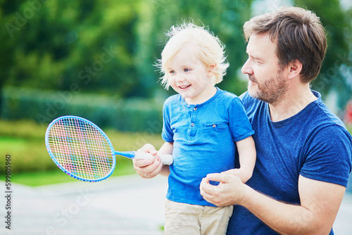 Little boy playing badminton with dad on the playground