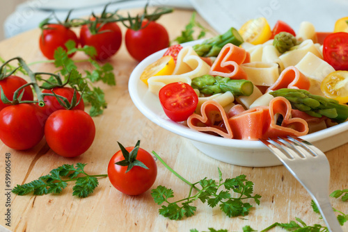 Romantic dinner. Delicious heart-shaped pasta with tomatoes, asparagus and fresh herbs