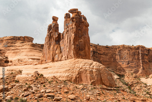 The Three Gossips red sandstone formation in the arid desert landscape of Arches National Park Utah with storm clouds.