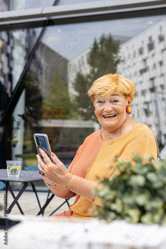 Portrait of a mature 80 years old emotional woman writing a message on mobile phone 