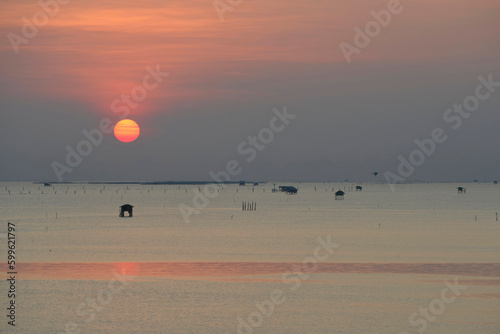 Fishing boat is sailing in aquacultural field in a sunrise time