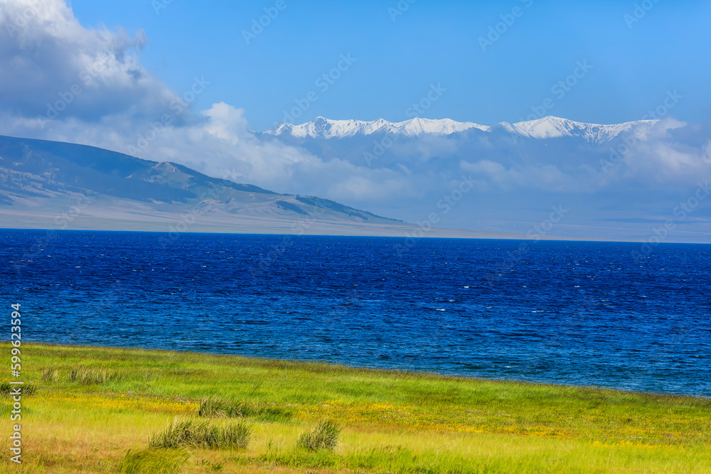 Beautiful Sayram Lake natural scenery in Xinjiang, China. Green meadow and lake with snow mountains landscape in summer. Beautiful Sayram Lake natural scenery in Xinjiang, China. Green meadow and lake with snow mountains landscape in summer.